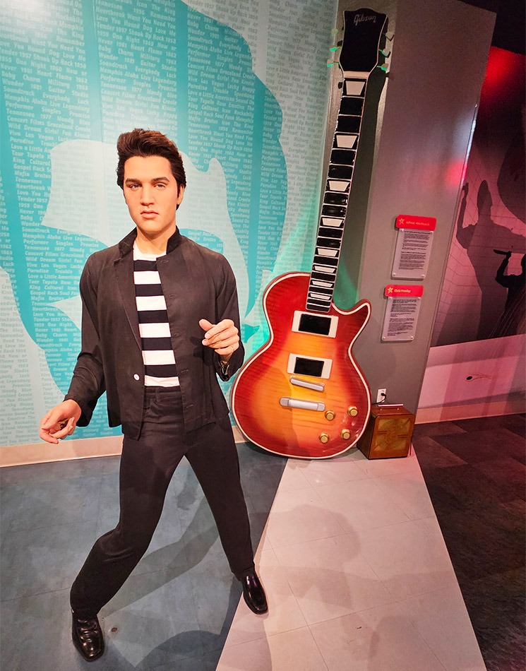 ストライプシャツのエルヴィス・プレスリーの蝋人形と巨大ギターの背景セット